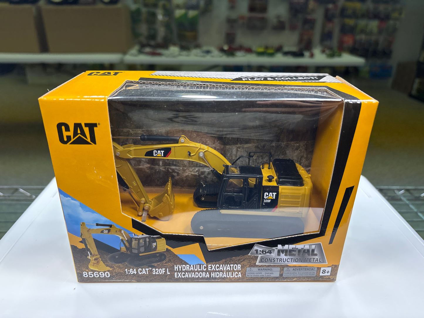 Model excavator in a CAT branded box on a white surface with a blurred background