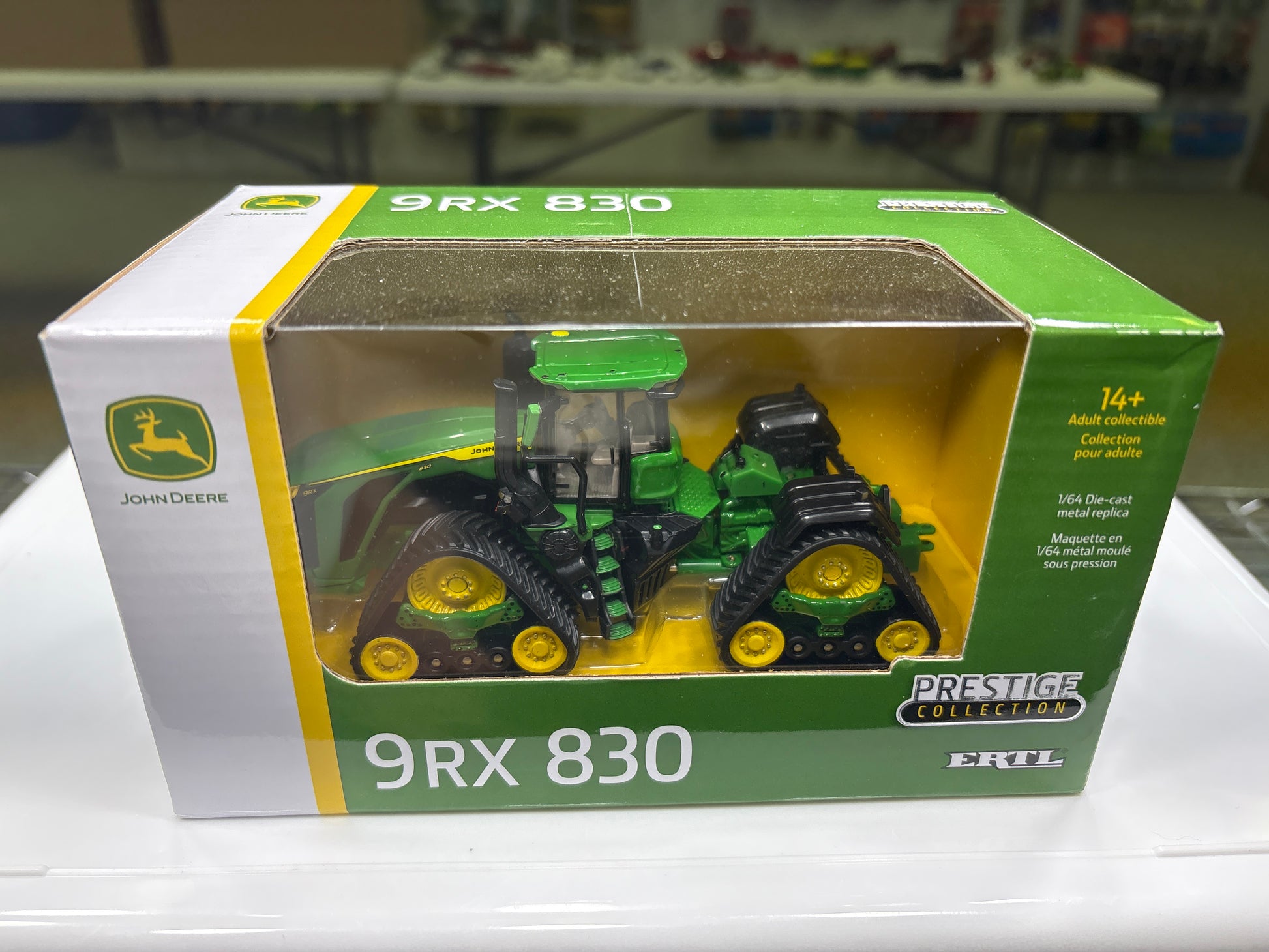 John Deere toy tractor in a green and white box on a white surface.