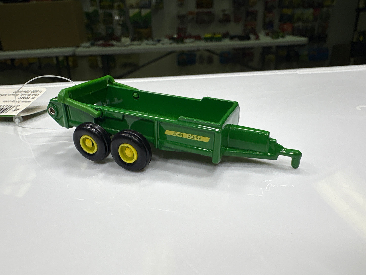 Green toy trailer with yellow wheels on a white surface