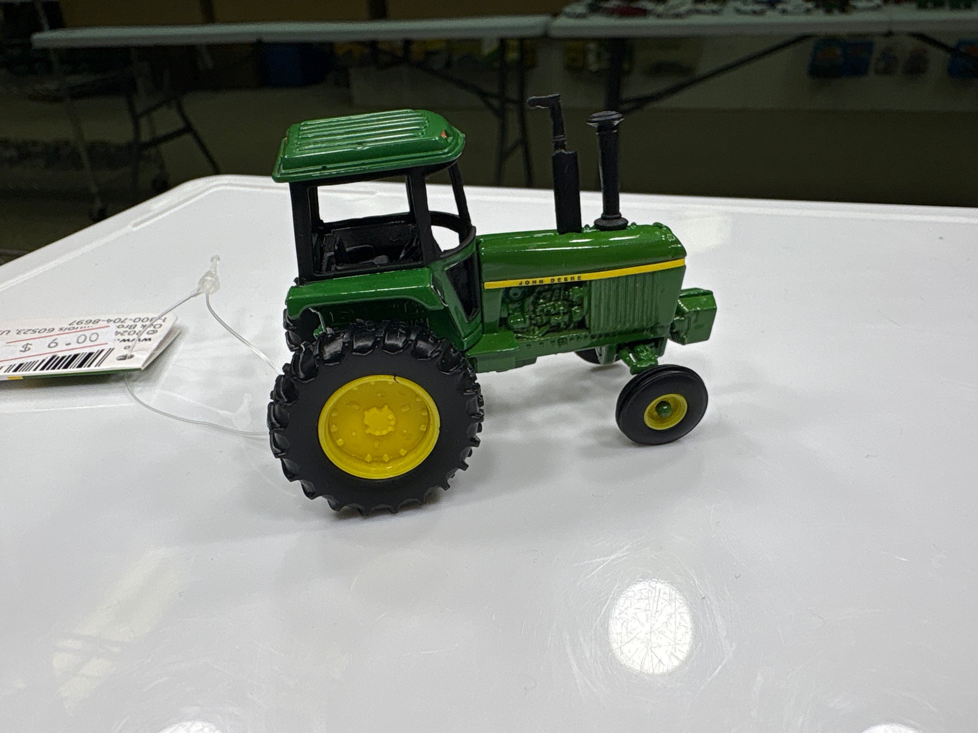 Green toy tractor on a white surface with a blurred background