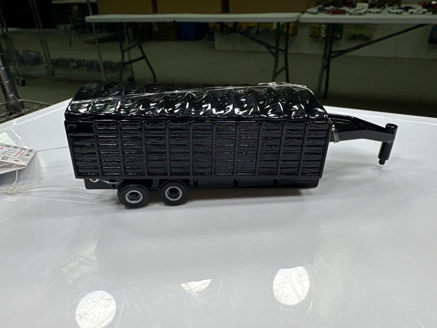 Black trailer model on a white surface with a blurred indoor background