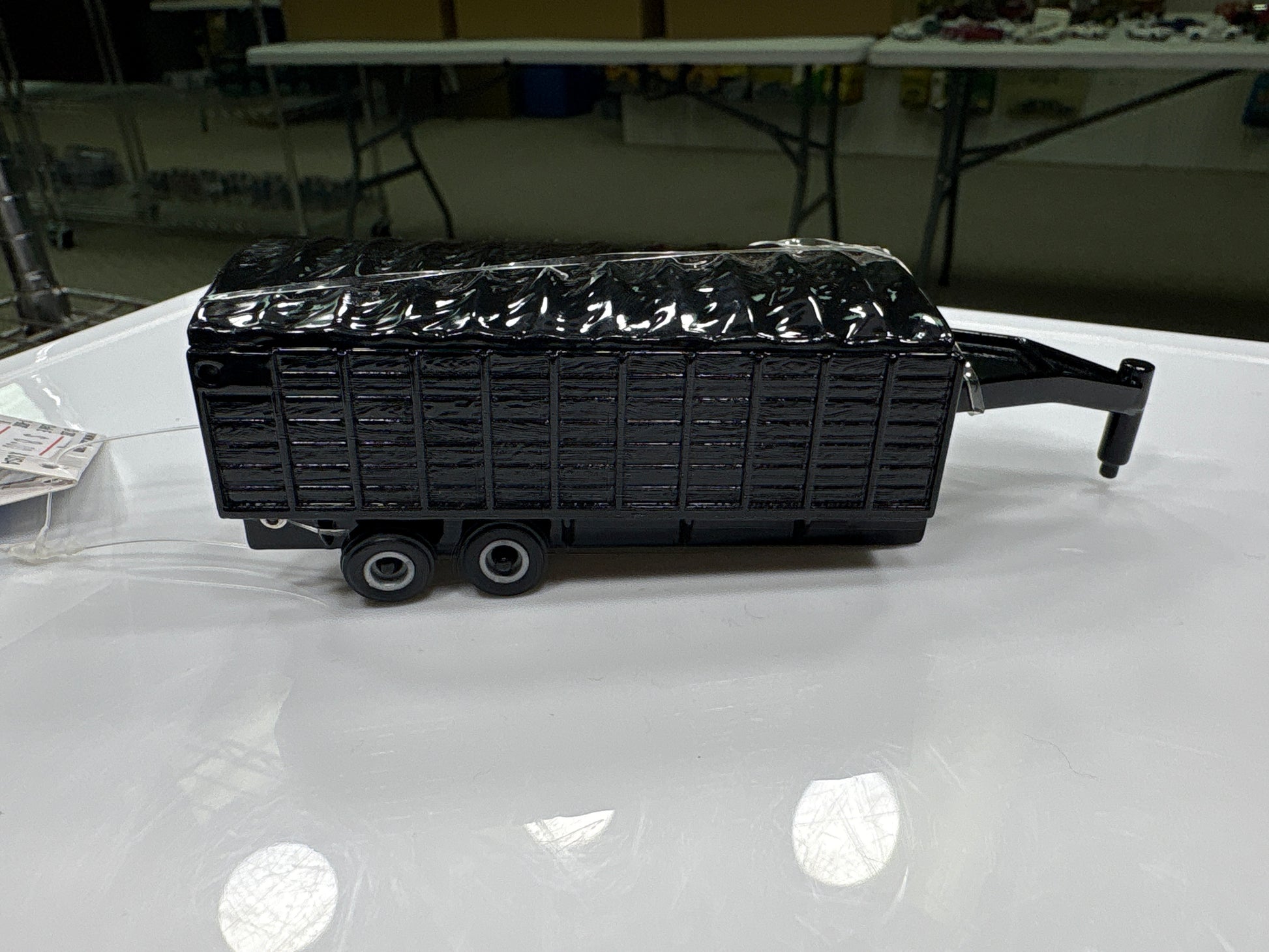 Black trailer model on a white surface with a blurred indoor background