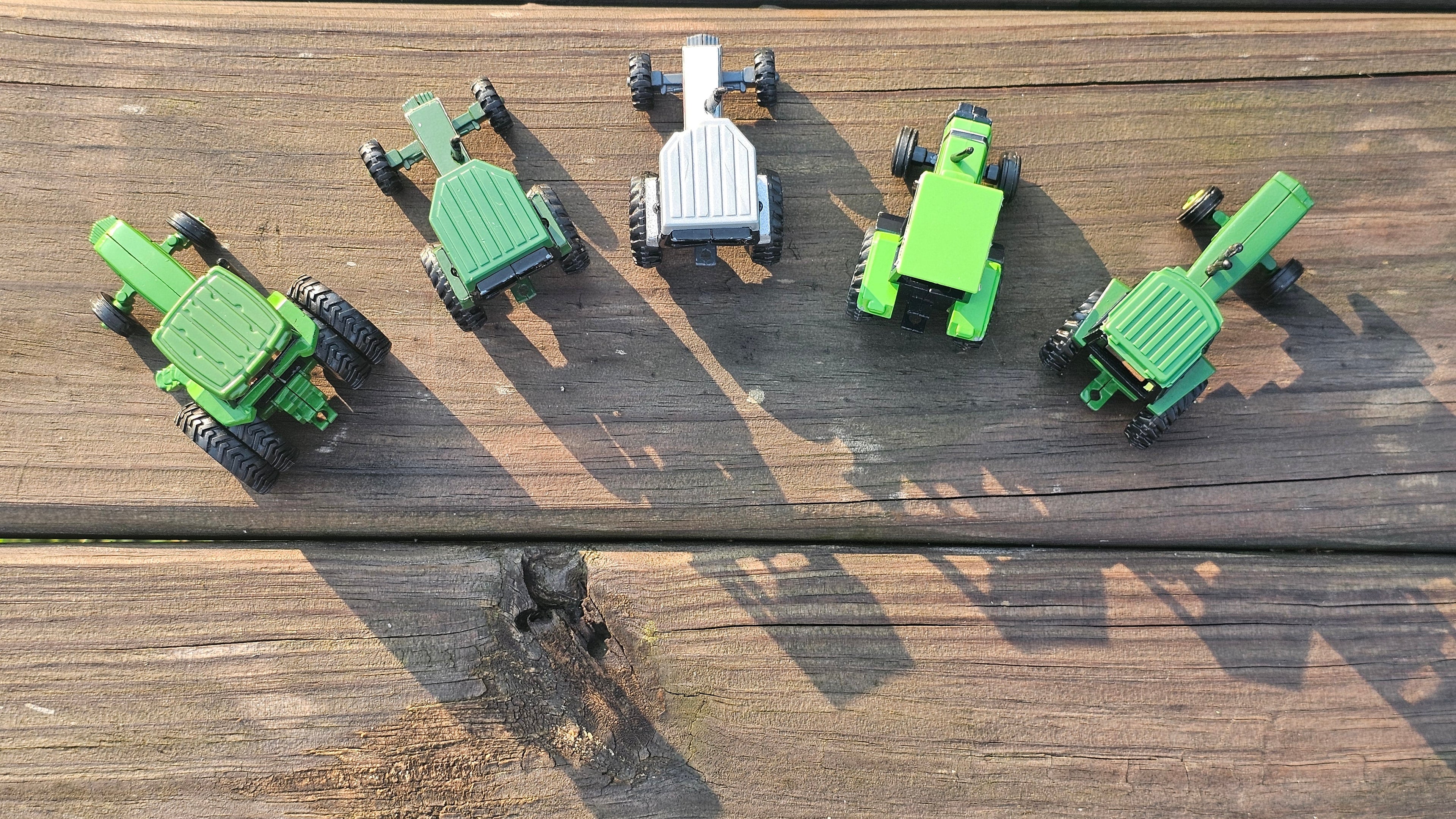 Top-down view of five farm toy tractors on a wooden surface – Mast Farm Toys